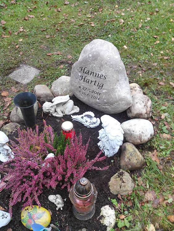 Grab aus "Findlingen", Schrift graviert und farbig ausgelegt.